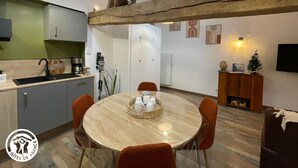 Eine moderne Küche mit einem runden Esstisch, orangefarbenen Stühlen und einem Holzbalken an der Decke.