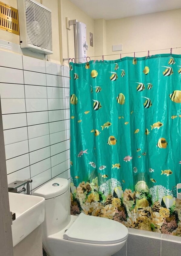 Un bagno con il water, un lavandino e una tenda da doccia con un motivo a pesci.