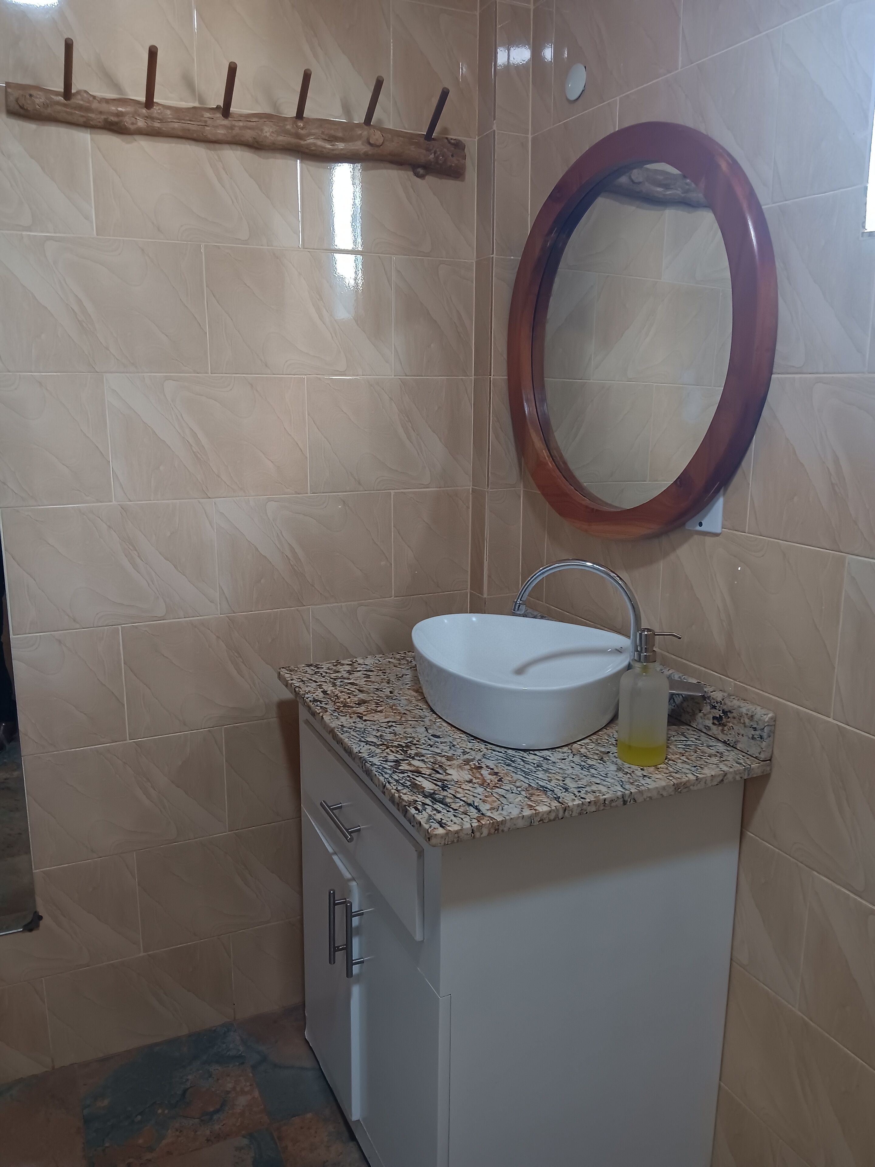 Un baño con un lavabo blanco, un estante de madera y un espejo.