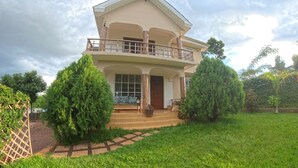 A two-story house with a balcony, a front porch, and a well-maintained lawn. - kili Kivuli  (Moshi)