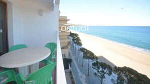 A balcony with a table and chairs, overlooking a beach with a clear sky. - Cozy apartment with WiFi and parking in Platja d'Aro (Platja d'Aro)