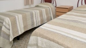 A bedroom with two single beds, a wooden nightstand, and a plain wall. - Cozy apartment with WiFi and parking in Platja d'Aro (Platja d'Aro)