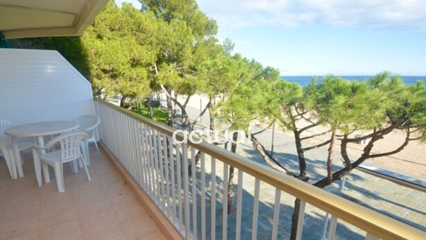 A balcony with a white railing, a small table, and chairs. There are trees and a view of the sea. - 1-Bed Apt in Platja d'Aro with Terrace & Parking (Platja d'Aro)
