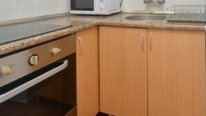 A kitchen with wooden cabinets, a microwave, a sink, and a stainless steel range hood. - 1-Bed Apt in Platja d'Aro with Terrace & Parking (Platja d'Aro)