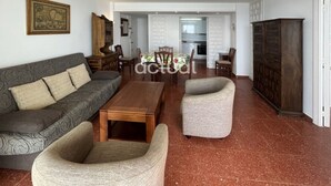 Una sala de estar con un sofá, dos sillones, una mesa de centro y un comedor con sillas y una mesa.