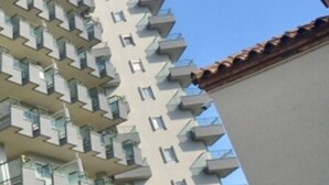 Un edificio alto con múltiples balcones y un cielo despejado.