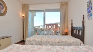 A bedroom with a bed, a nightstand, a lamp, and a window with curtains. - 1-Bedroom Apartment with Terrace & Parking in Platja d'Aro (Platja d'Aro)