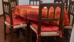 A dining table with a red tablecloth, surrounded by wooden chairs with red cushions. - 1-Bedroom Apartment with Terrace & Parking in Platja d'Aro (Platja d'Aro)