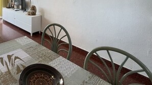 Uma sala de jantar com uma mesa posta para dois, um sofá e um armário branco.