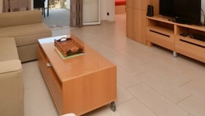 A living room with a beige sofa, a wooden coffee table, and a TV stand with a flat-screen TV. - Apartment in Platja d'Aro near the beach with air conditioning and WiFi (Platja d'Aro)