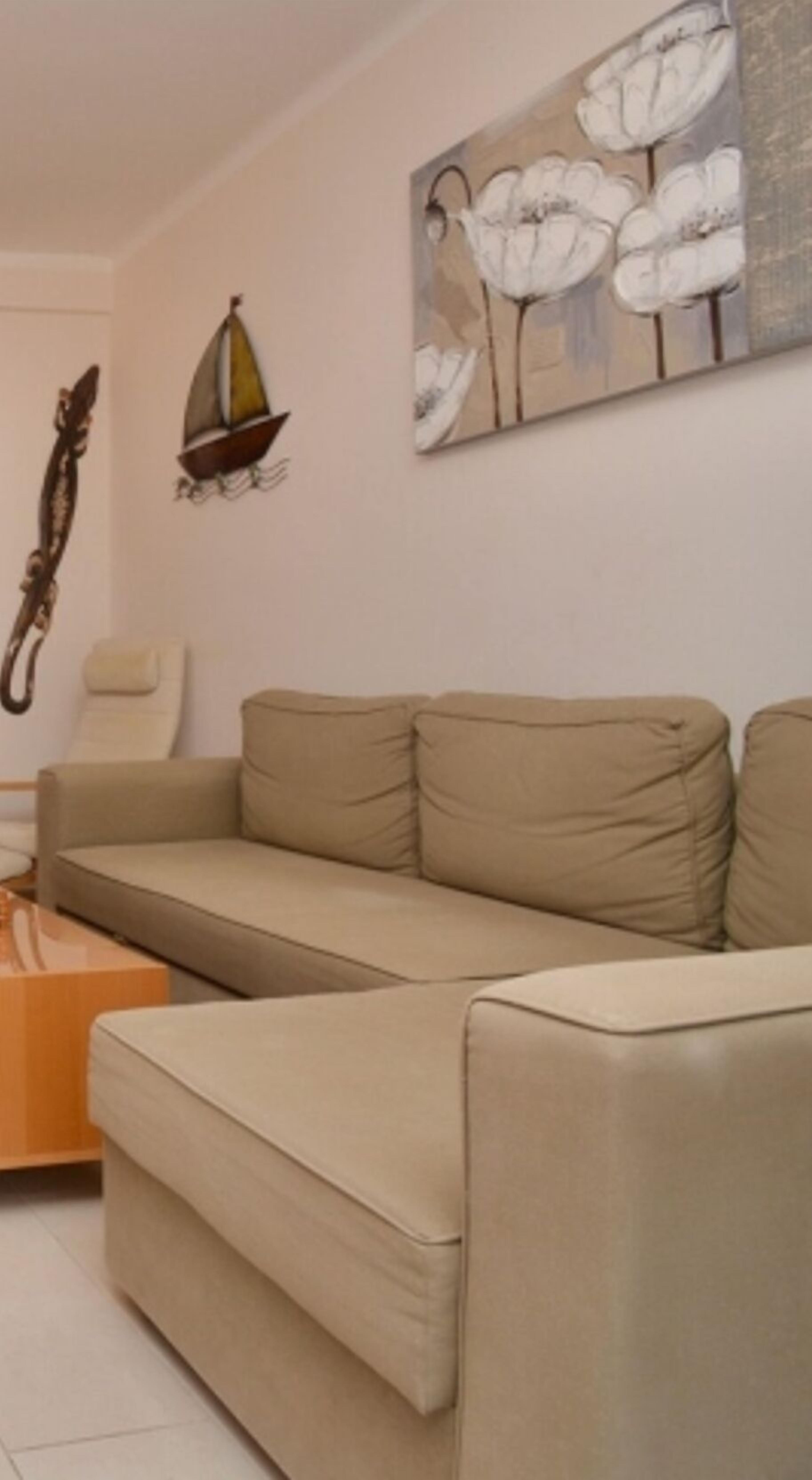 Ein Wohnzimmer mit einem beigefarbenen Sofa, einem Couchtisch und einem Wandbild mit Blumen.