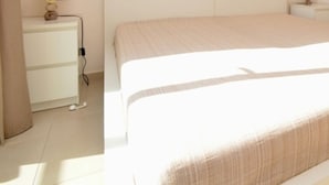 A neatly made bed in a room with a white dresser and a small bedside table. - Apartment in Platja d'Aro near the beach with air conditioning and WiFi (Platja d'Aro)
