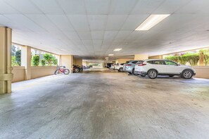 Een overdekte parkeerplaats met auto's en fietsen.