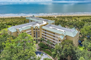 Un hôtel à plusieurs étages doté d’une piscine, entouré d’une végétation luxuriante et offrant une vue sur la plage.
