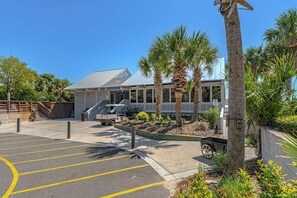 A parking lot with marked spaces, a building with a metal roof, and palm trees.