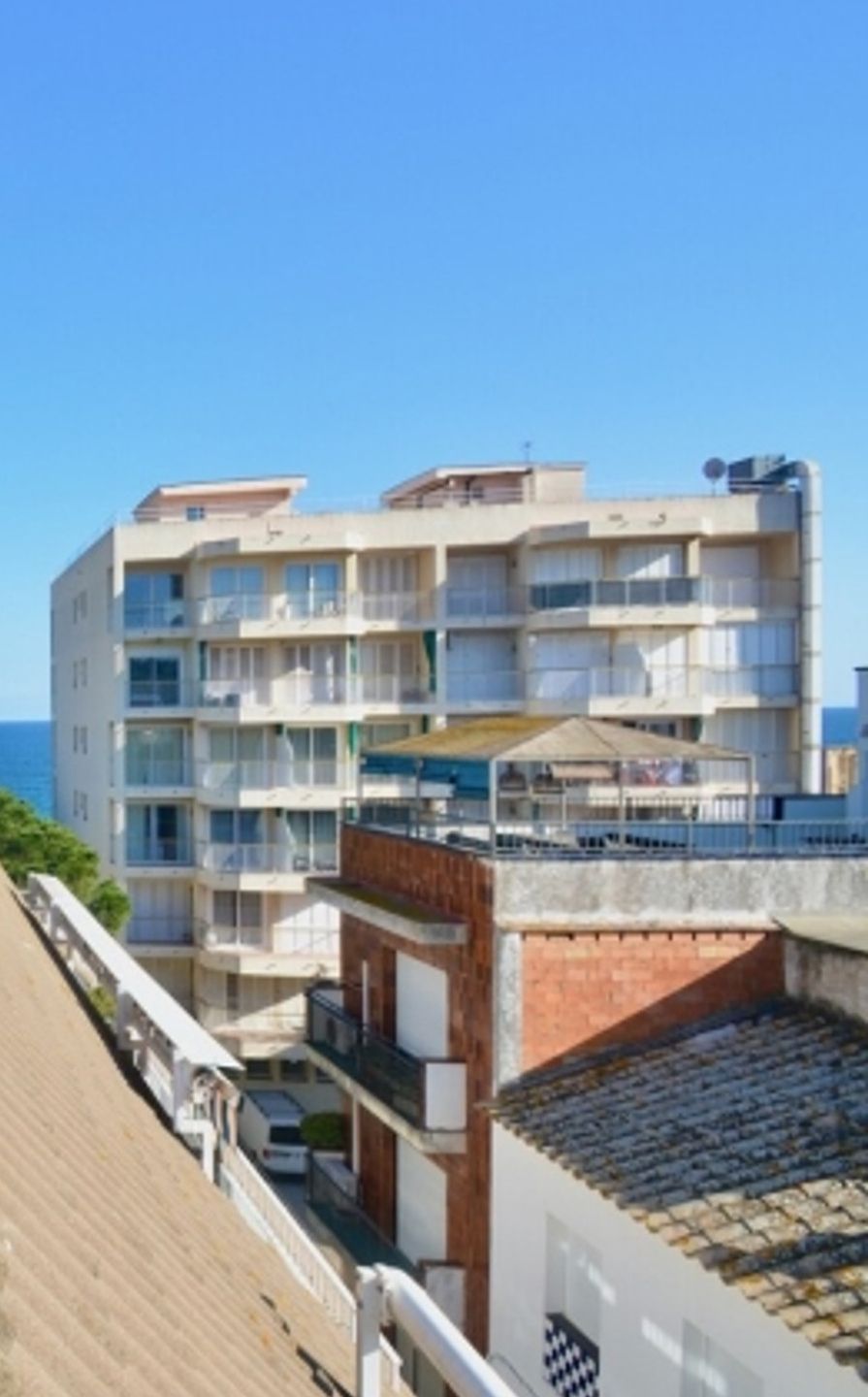 Ett hotell med flera våningar, balkonger, ett takförsett utomhusområde och utsikt över havet.