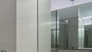 Een moderne badkamer met een witte wastafel, een grote spiegel en een kast met lades.