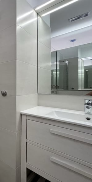 Un baño con un lavamanos blanco, un espejo y una puerta.