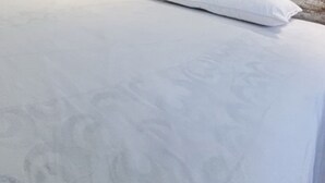 Een bed met een witte matras en een wit kussen.