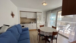 A compact living space with a kitchenette, a dining area with a table and chairs, a sofa, and a balcony with plastic chairs. - Seaside apartment with terrace, optional AC, parking, and WIFI (Platja d'Aro)