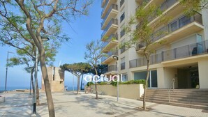 A modern building with a flat roof, large windows, and a paved walkway. - Seaside apartment with terrace, optional AC, parking, and WIFI (Platja d'Aro)