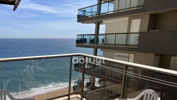 A balcony with a glass railing overlooking the ocean, featuring two white plastic chairs and a small table. - Seaside apartment with terrace, optional AC, parking, and WIFI (Platja d'Aro)