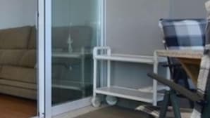 A room with a sliding glass door leading to a balcony, a small table with a chair, and a blue and white checkered chair. - 3-bedroom beachfront apartment with terrace in Platja d'Aro (Platja d'Aro)