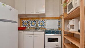 A compact kitchen with white cabinets, a stove, a microwave, and a shelf with a coffee maker. - 2-bedroom apartment with terrace, sea view and parking in Platja d'Aro (Platja d'Aro)