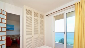 A bedroom with a bed, a sliding glass door to a balcony, a red chair, and a painting on the wall. - 2-bedroom apartment with terrace, sea view and parking in Platja d'Aro (Platja d'Aro)