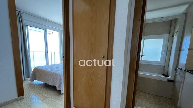 A room with a bed, a wooden door, and a window. - Costa Brava: 9th-floor apartment, 2 bedrooms, terrace, parking, WIFI (Platja d'Aro)