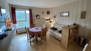 A cozy room with a dining table, chairs, a sofa, and a small bookshelf. - Cozy studio 4 ppl at slopes' foot (Laveissière)