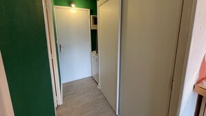 A narrow hallway with green walls, a white door, and a white wardrobe. - Cozy studio 4 ppl at slopes' foot (Laveissière)