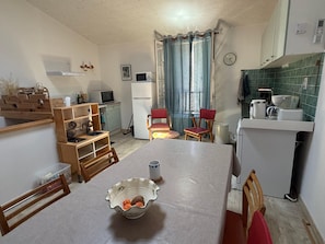A compact kitchen with a dining table, chairs, a microwave, a refrigerator, and a sink. - Charming village house in Argelès-sur-Mer close to amenities (Argelès-sur-Mer)