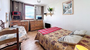 A cozy bedroom with a bed, a desk, a chair, a window with a view, and a poster on the wall. - Ski-in/Ski-out Studio, 2 guests, Le Corbier Residence (Le Corbier)