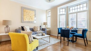 Una sala moderna con un sofá, un sillón amarillo y un comedor con sillas azules.