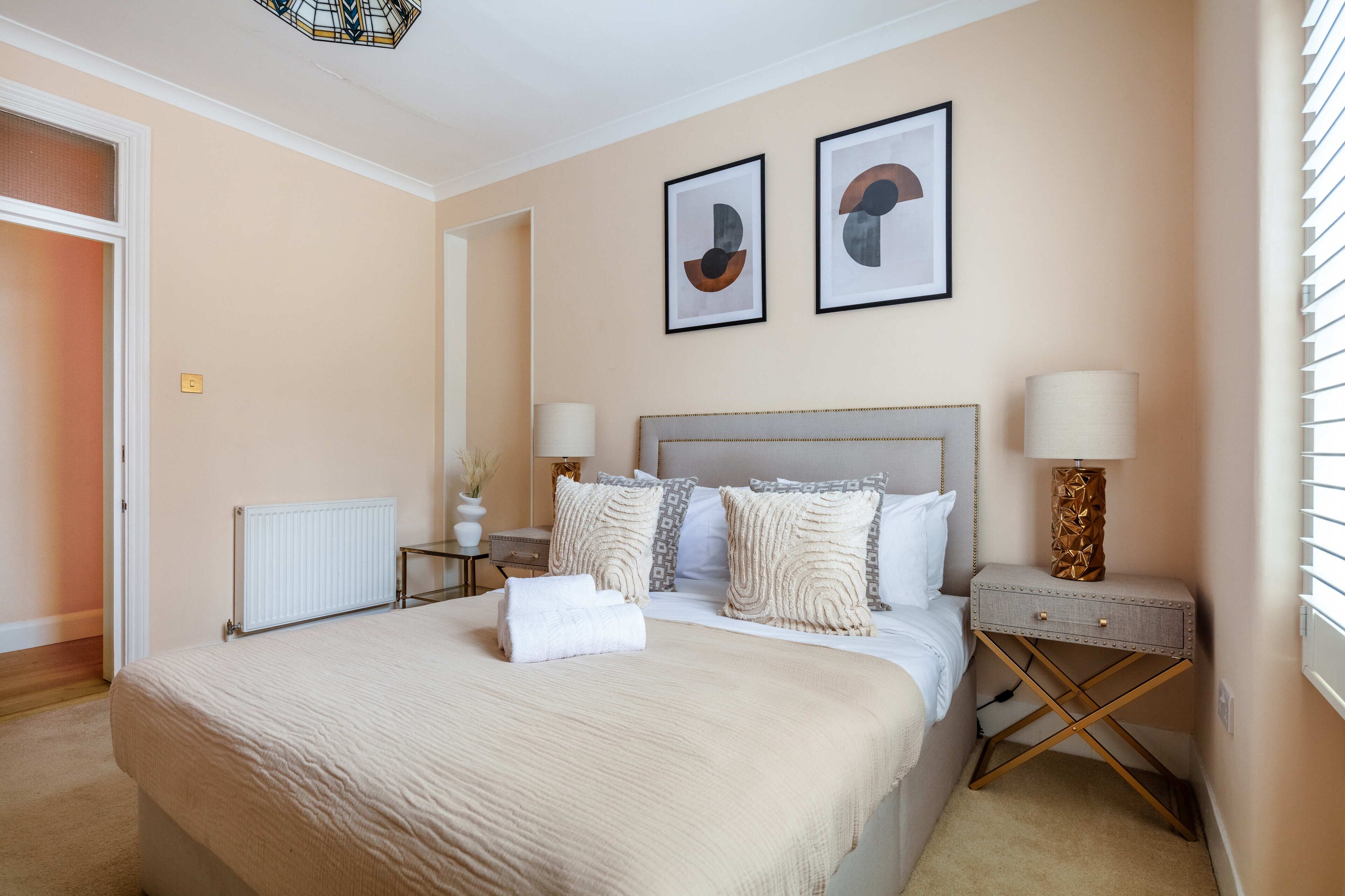 A neatly arranged bedroom with a large bed, bedside tables, and framed artwork on the wall.
