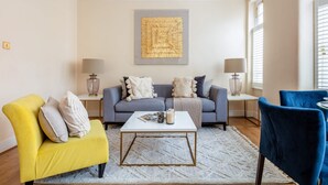 Una sala de estar con un sofá, dos sillones, una mesa de centro y una lámpara a cada lado.