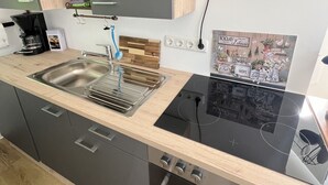 Moderni keittiö, jossa on sisäänrakennettu liesi, uuni ja pesuallas.