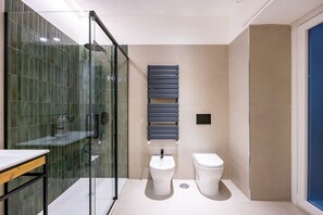 A modern bathroom with a glass shower enclosure, a white sink, and a toilet.