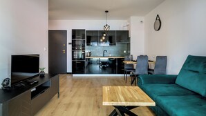 A modern living room with a TV, sofa, and wooden coffee table. - RentPlanet - Apartament Czysta (Wroclaw)