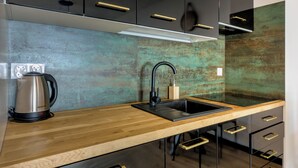 A modern kitchen with a wooden countertop, black cabinets, and a stainless steel kettle. - RentPlanet - Apartament Czysta (Wroclaw)
