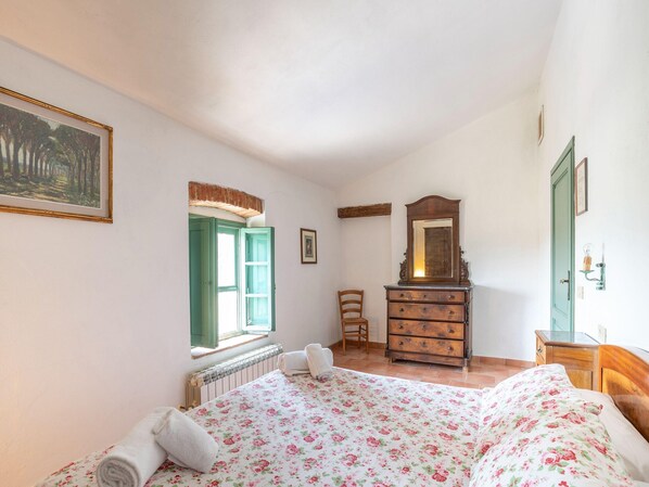 Un dormitorio con cama, cómoda y ventana con vista a árboles.