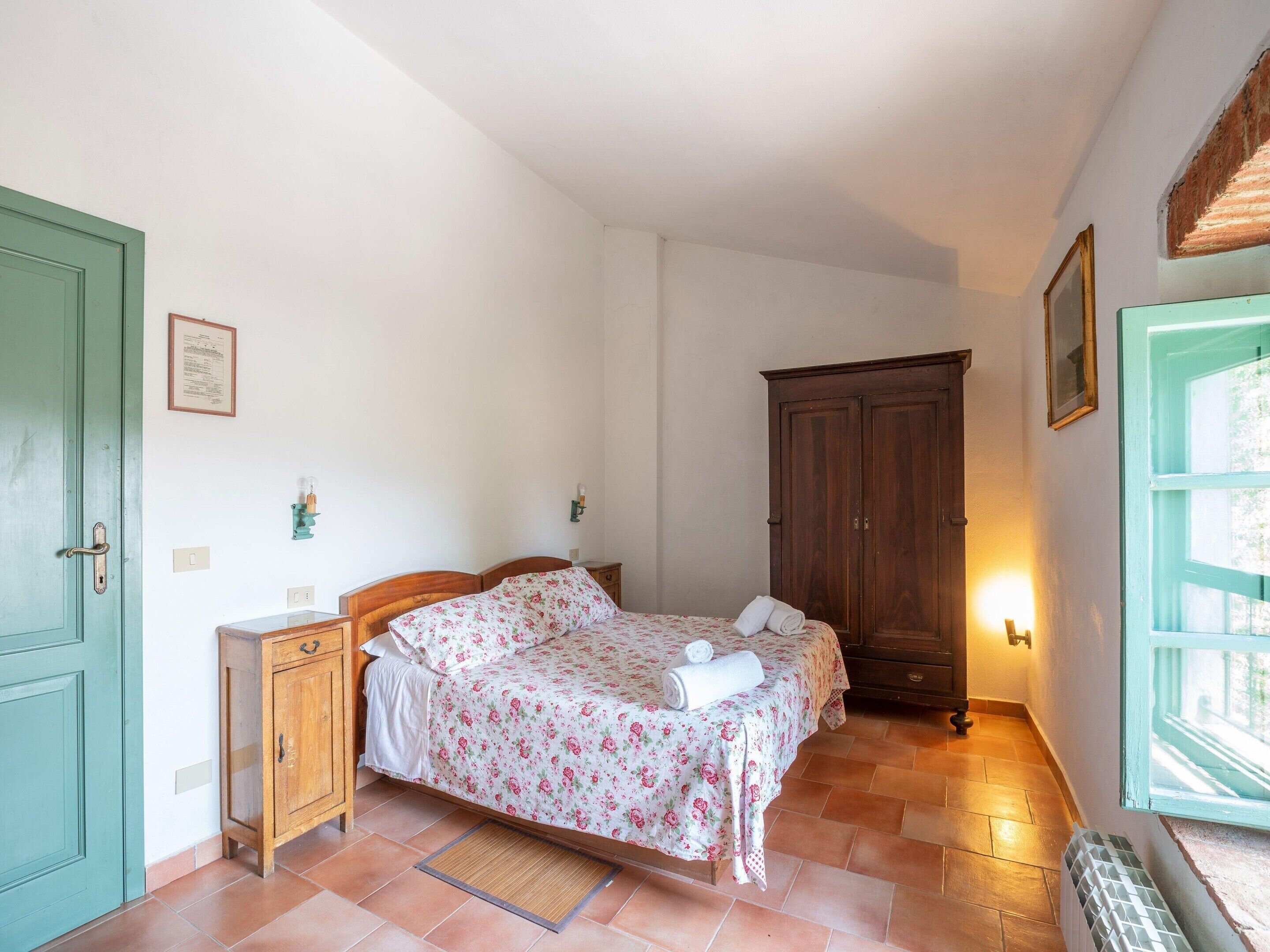 A bedroom with a bed, a wardrobe, a radiator, and a window.