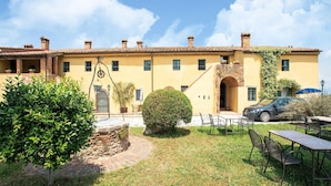 A yellow building with multiple windows, a stone staircase, and outdoor seating. - Apartment in Tuscany Near Pisa and Beaches (Collesalvetti)