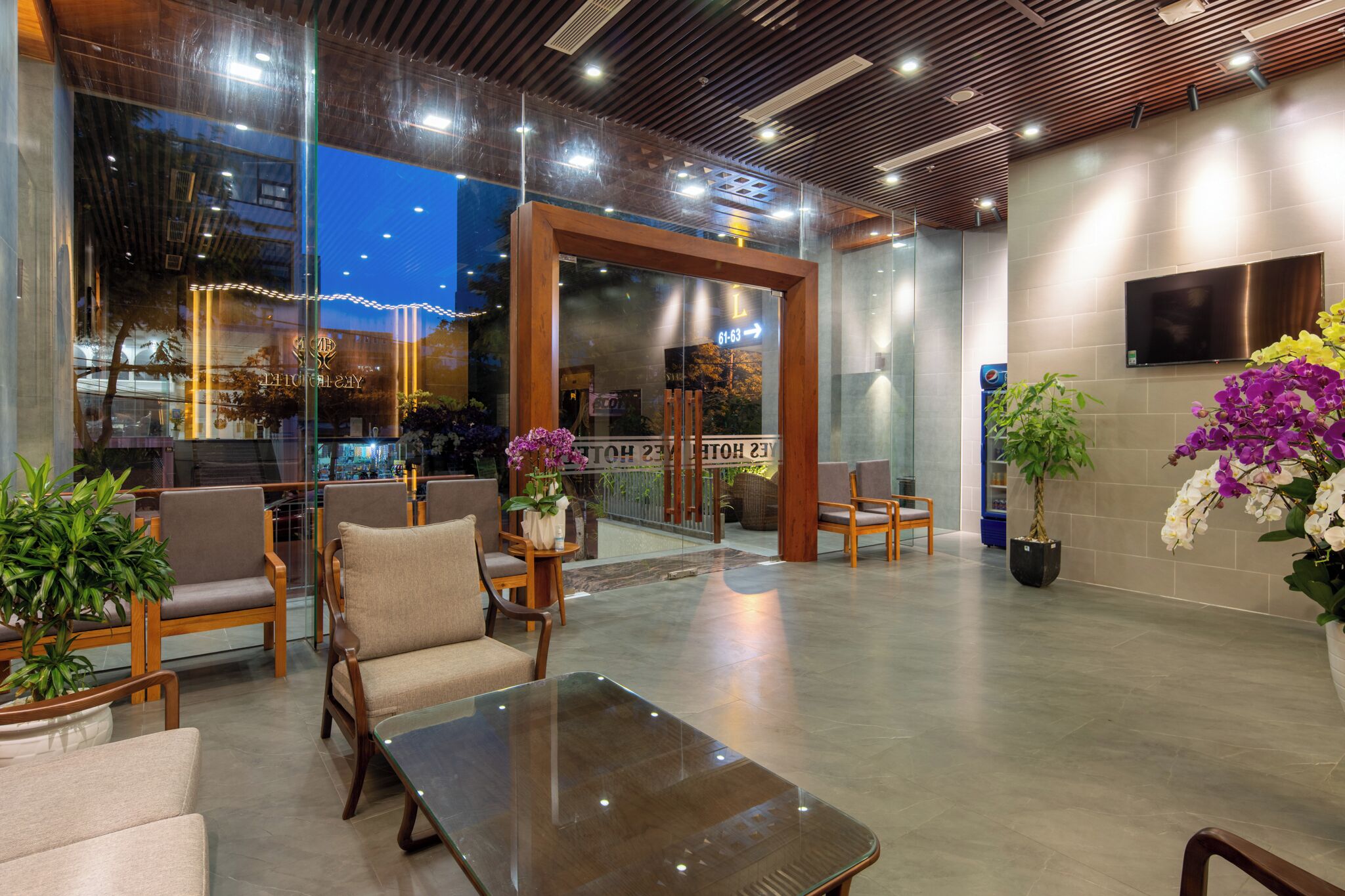 A modern lobby with seating areas, a reception desk, and a large glass window.