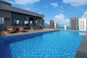 Un bâtiment moderne doté d’une piscine, d’un espace extérieur aménagé et offrant une vue sur l’océan et le paysage urbain.