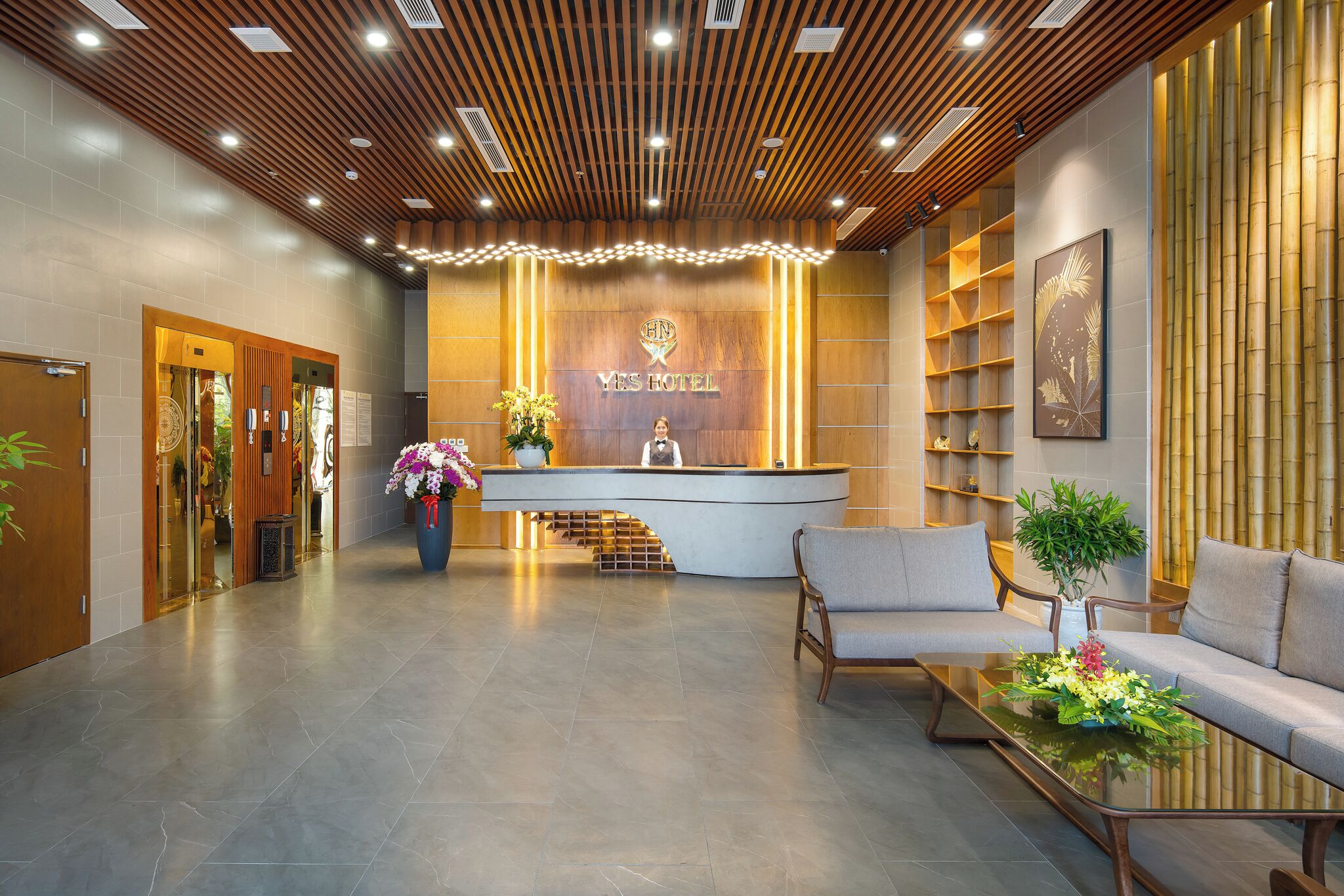 A hotel reception area with a wooden reception desk, a sofa, and a coffee table.