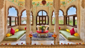 Una habitación tradicional con arcos decorativos, una zona de estar central con cojines y vistas al paisaje.