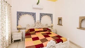 A bedroom with a large bed, two ornate wall mirrors, a white ceiling, and a floral curtain.