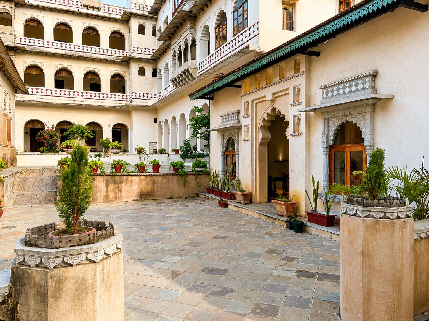 Un patio con varios arcos, plantas en macetas y suelo de piedra.